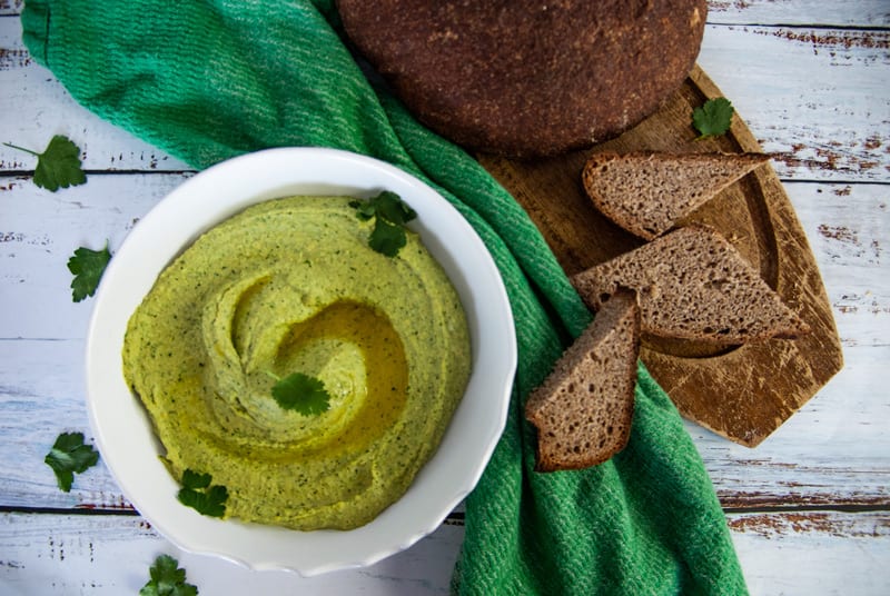 Overhead shot of Cilantro Jalapeno Hummus with sliced wheat bread on the side