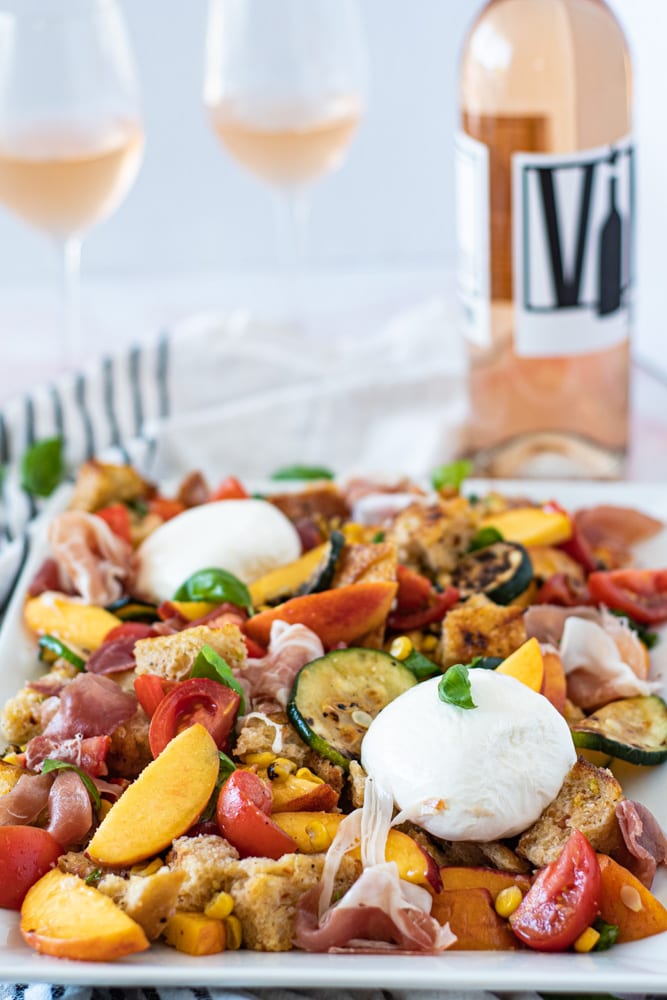 Side shot of summer panzanella salad with wine in the backgroun