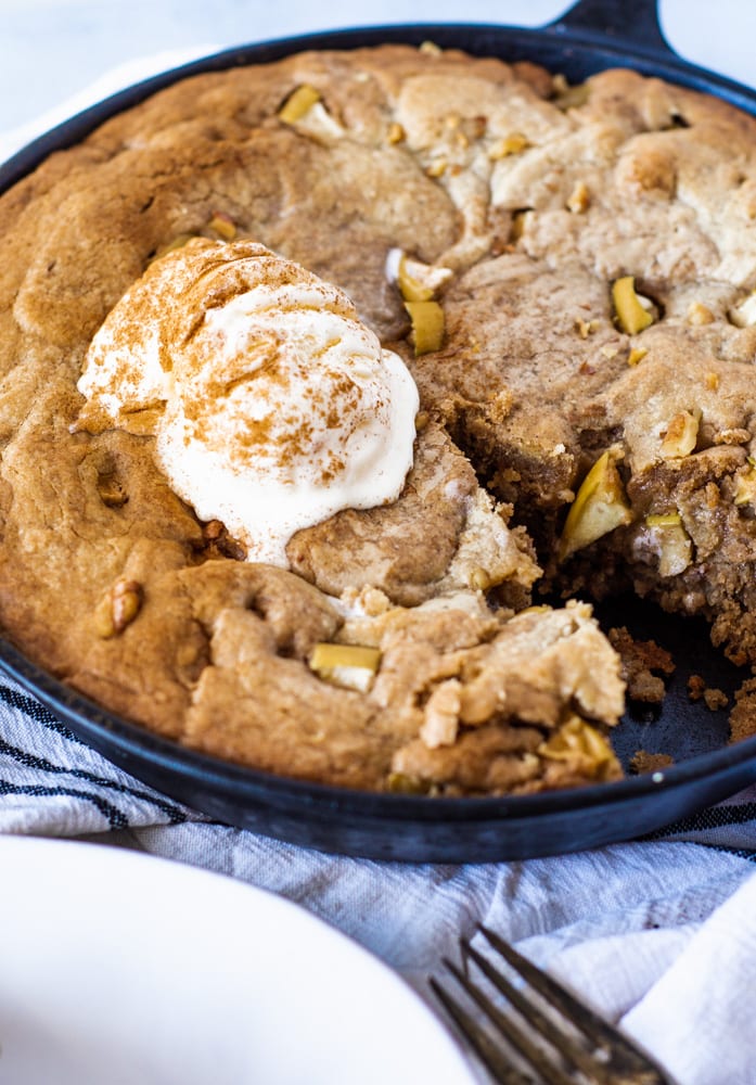 close up of Apple Cinnamon Blondie Bake with two scoops of Vanilla Ice Cream and two apples in back with a bite cut out